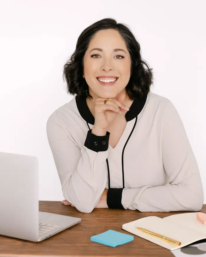 Angel Hepp, Founder and COO, smiling at her desk