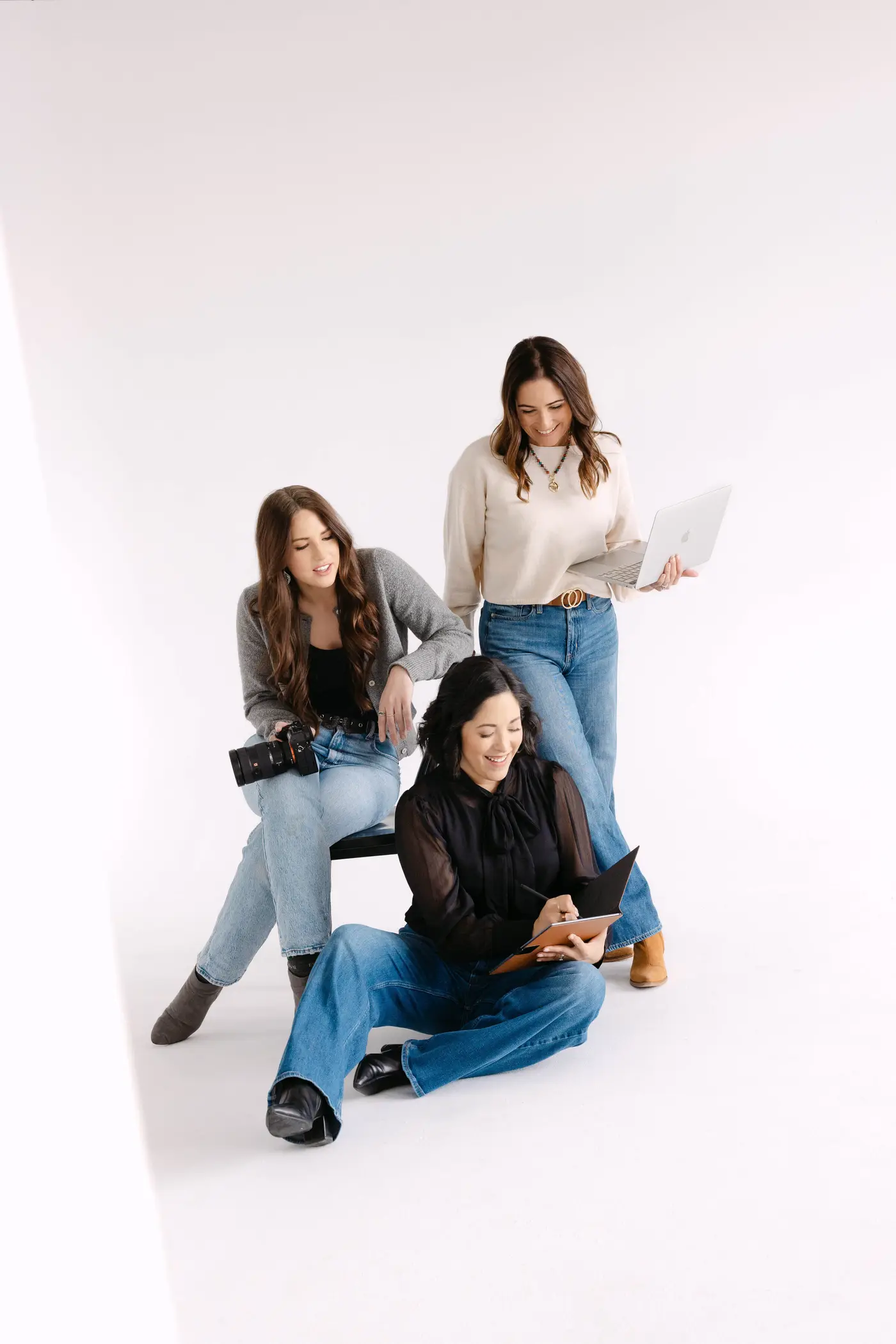 The three Salt Collective founders gathered around a camera and notebook