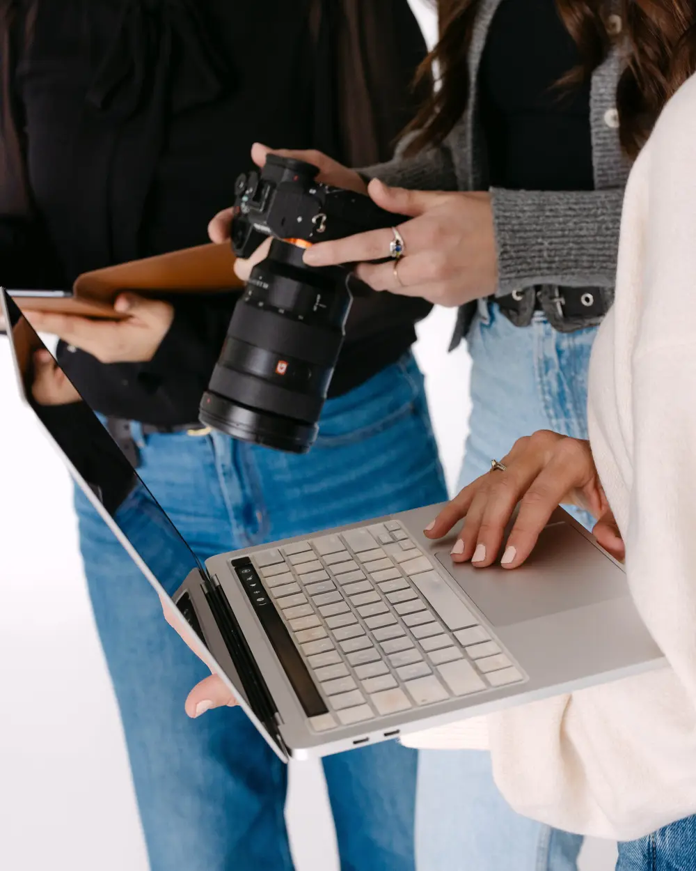 Hands holding a camera over an open laptop