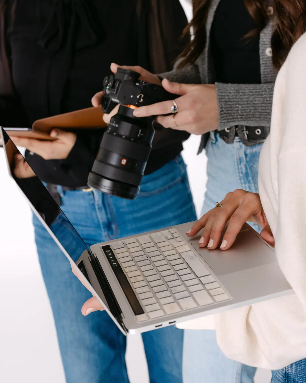 Hands holding a camera over an open laptop