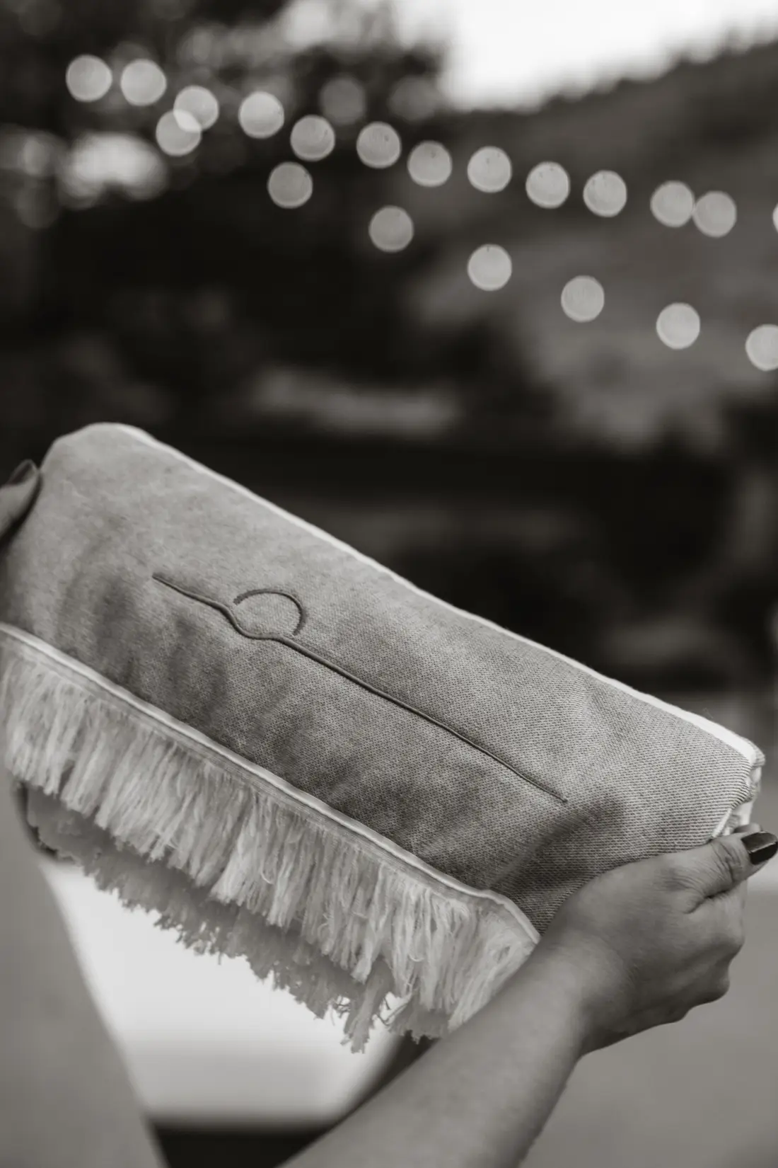 Black and white detail of a fringed leather clutch