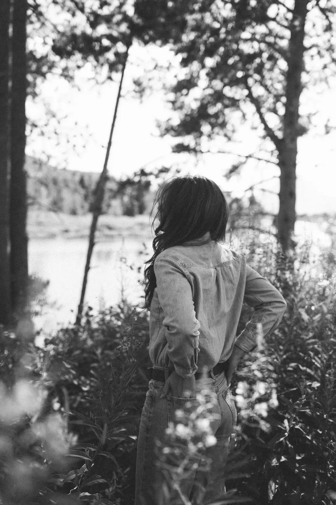 Black and white photo of a woman walking through trees