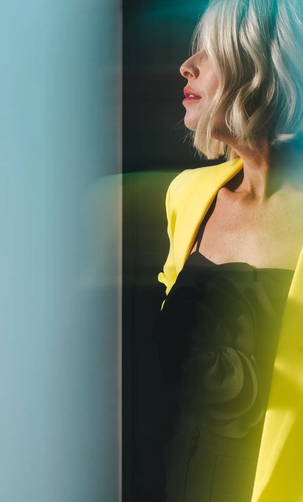Portrait of a woman in yellow against a teal backdrop