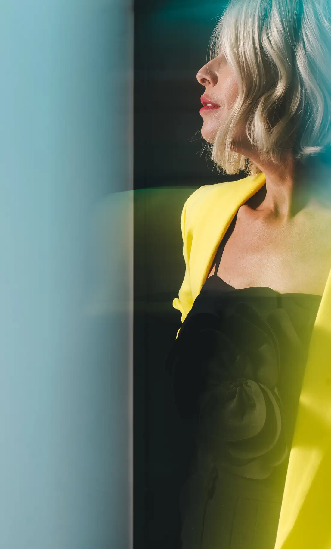 Portrait of a woman in yellow against a teal backdrop